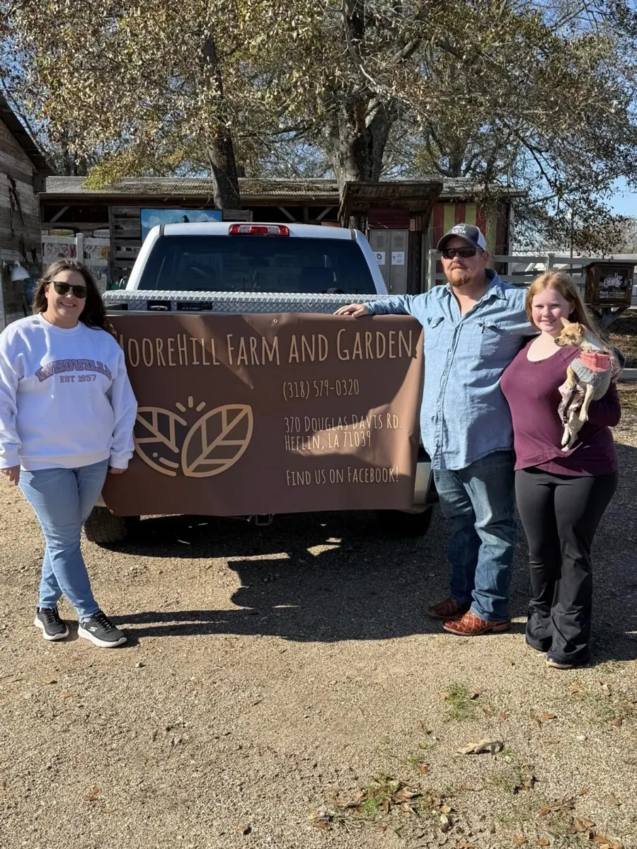 Moore Hill Farm family standing near the farm sign